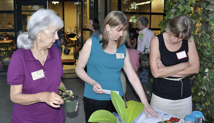 Kathleen Thompson, Kathryn Fields, and Monika Coleman participate in the plant swap during the Volunteer Potluck Dinner