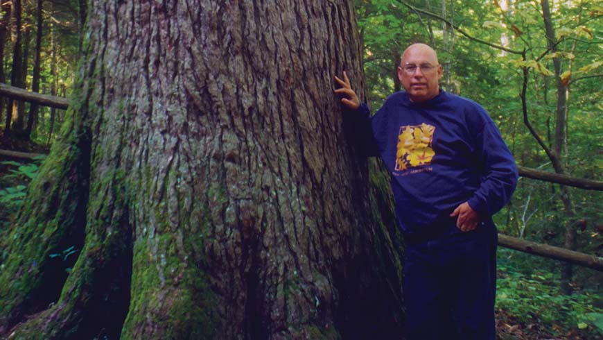 J. C. Raulston standing next to large tree trunk